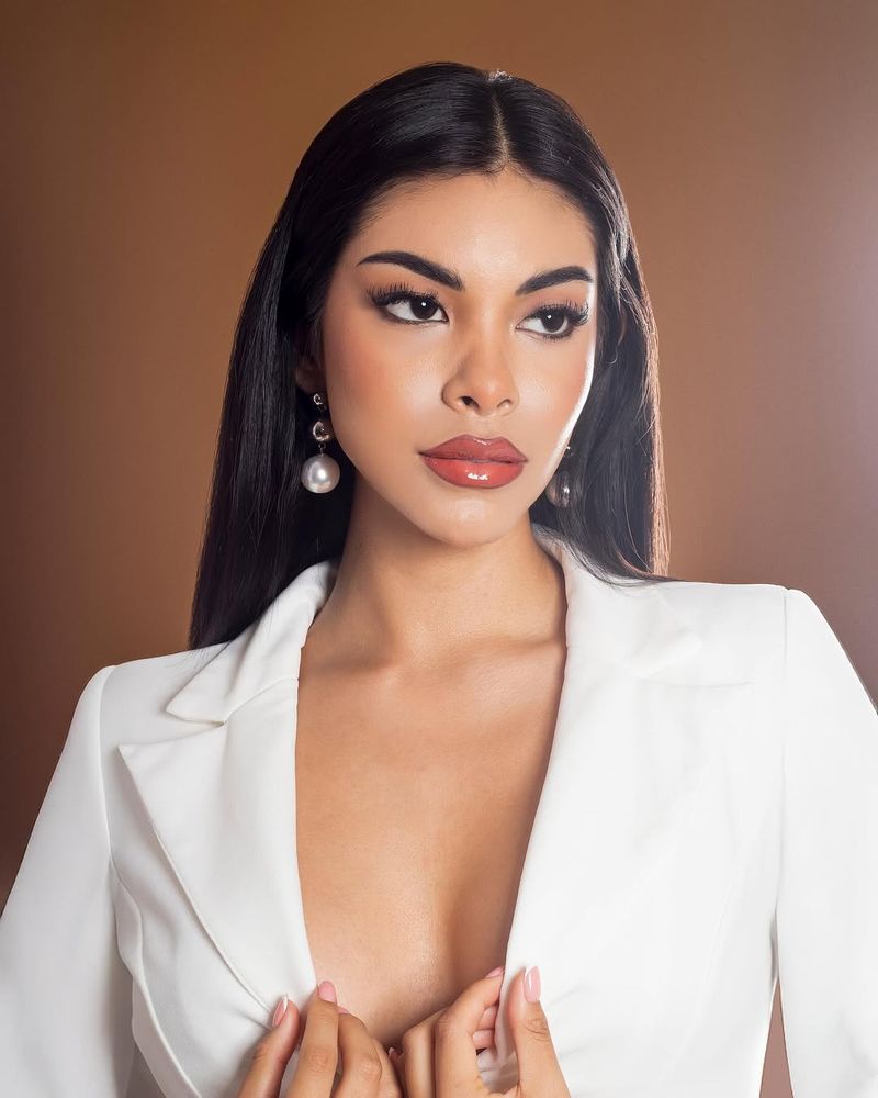 Alexandra en retrato de estudio: blazer blanco y aretes de perla sobre fondo bronce
