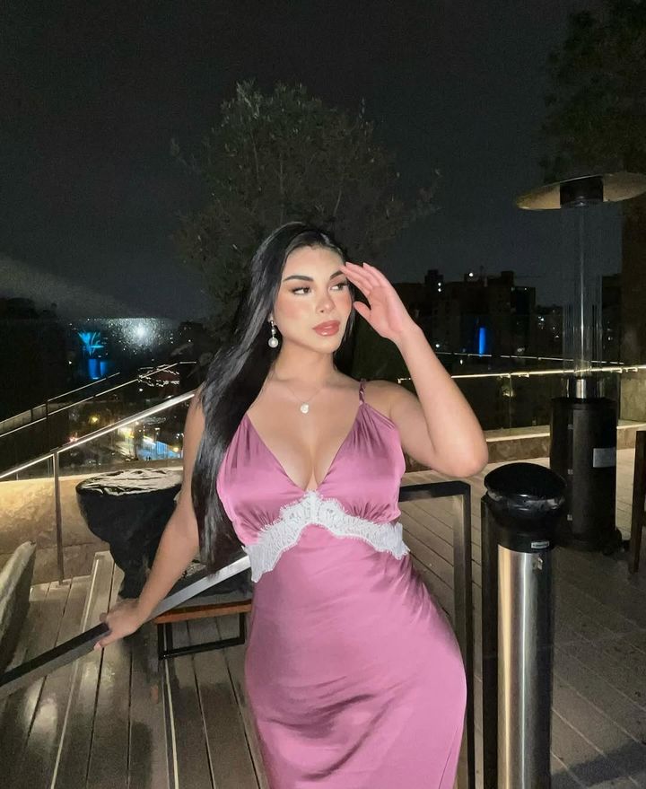 Alexandra de noche en una terraza, vestido de satén rosa y aretes de perla